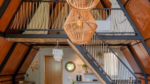A spacious loft with a high ceiling, exposed wooden beams, a central staircase, and a dining area with a round table and chairs. - Recanto Catarina (Cascavel)