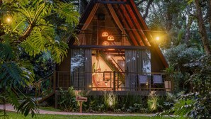 A rustic cabin with a glass facade, surrounded by lush greenery. - Recanto Catarina (Cascavel)