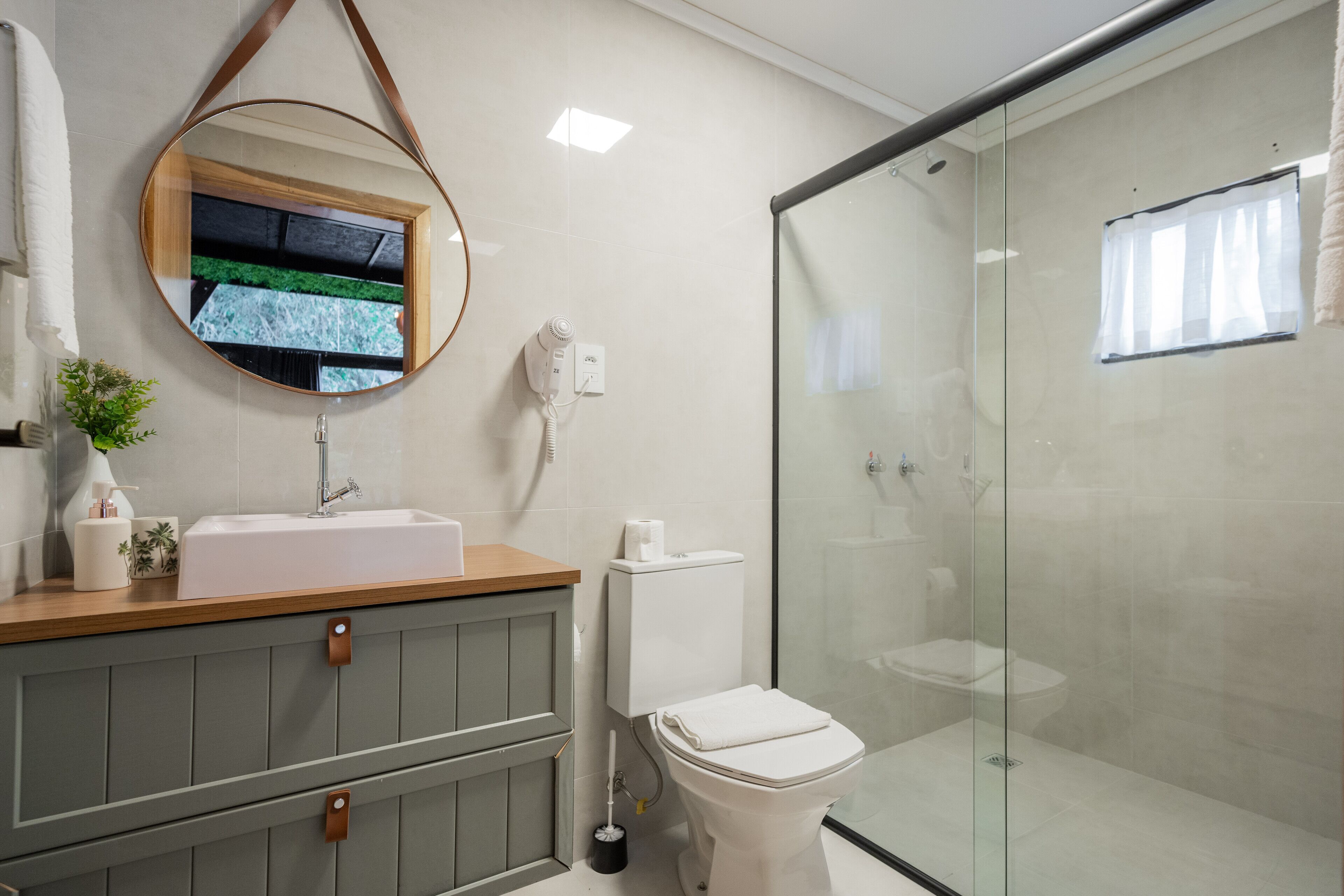 Un baño moderno con cabina de ducha de vidrio, tocador de madera y un inodoro.