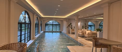 A spacious indoor swimming pool with seating areas and large windows.