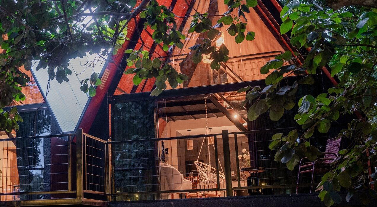 Un edificio moderno con techo triangular, ventanas amplias y un interior visible que incluye un comedor.