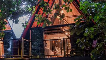 Un edificio moderno con techo triangular, ventanas amplias y un interior visible que incluye un comedor.