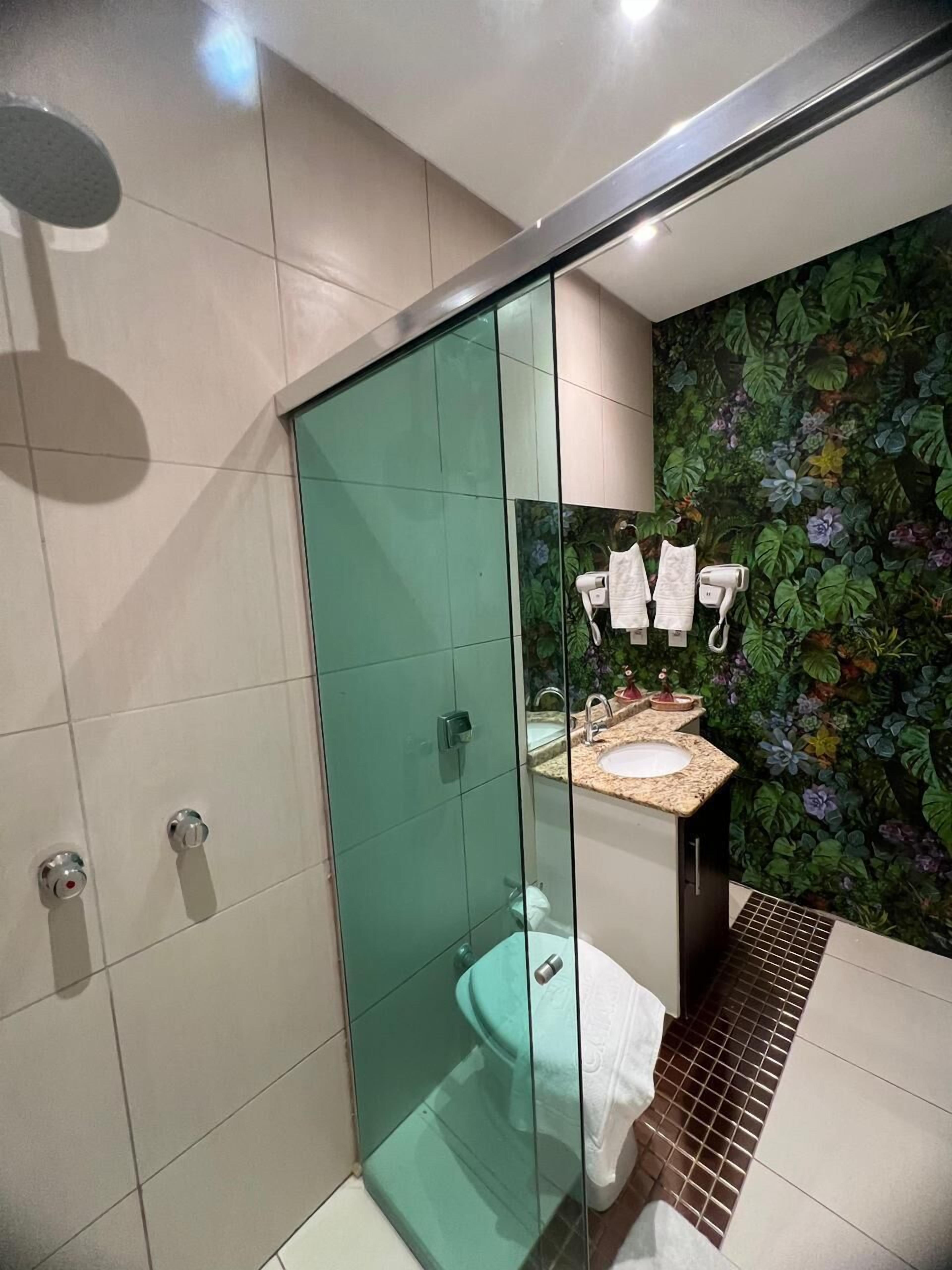 Een moderne badkamer met een douchecabine van glas, een toilet en een wastafel met decoratieve wand.