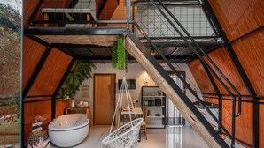 A spacious loft with a large bathtub, a hanging chair, and a staircase. - Recanto Catarina (Cascavel)