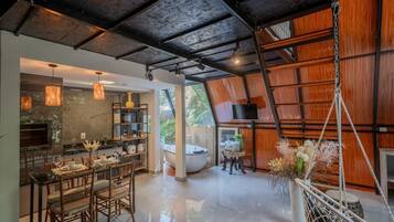 A modern kitchen with a dining area, a large window, and a hanging plant.