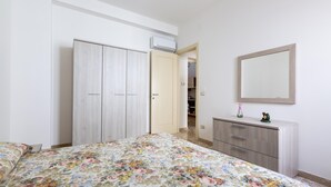 A bedroom with a floral bedspread, a wardrobe, a dresser, and a mirror on the wall.