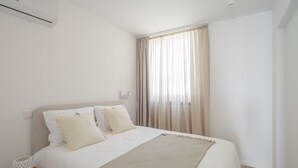 Une chambre d’hôtel moderne avec un grand lit, une table de chevet et une fenêtre avec des rideaux.