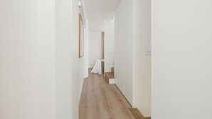 Un couloir étroit avec un plancher en bois et des murs blancs.
