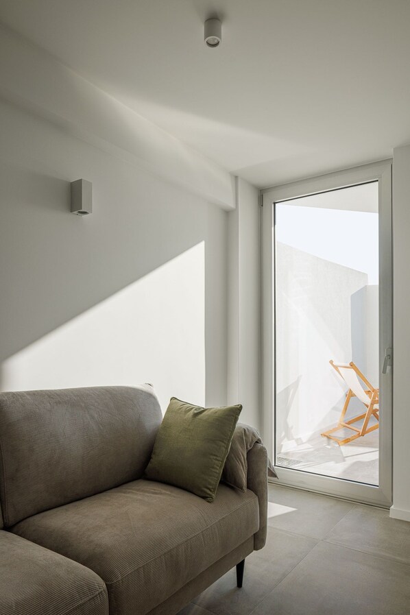 En moderne stue med sofa, glasdør til udendørs og en lampe i loftet.