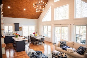 A spacious kitchen with a large island, wooden flooring, and a high ceiling with exposed beams. - Modern Luxury Rustic Home at Lake | Dogs Welcome (Farmington)