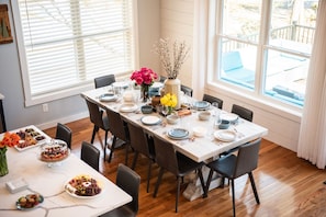 Een eetkamer met een lange tafel gedekt voor zes personen, omringd door stoelen.