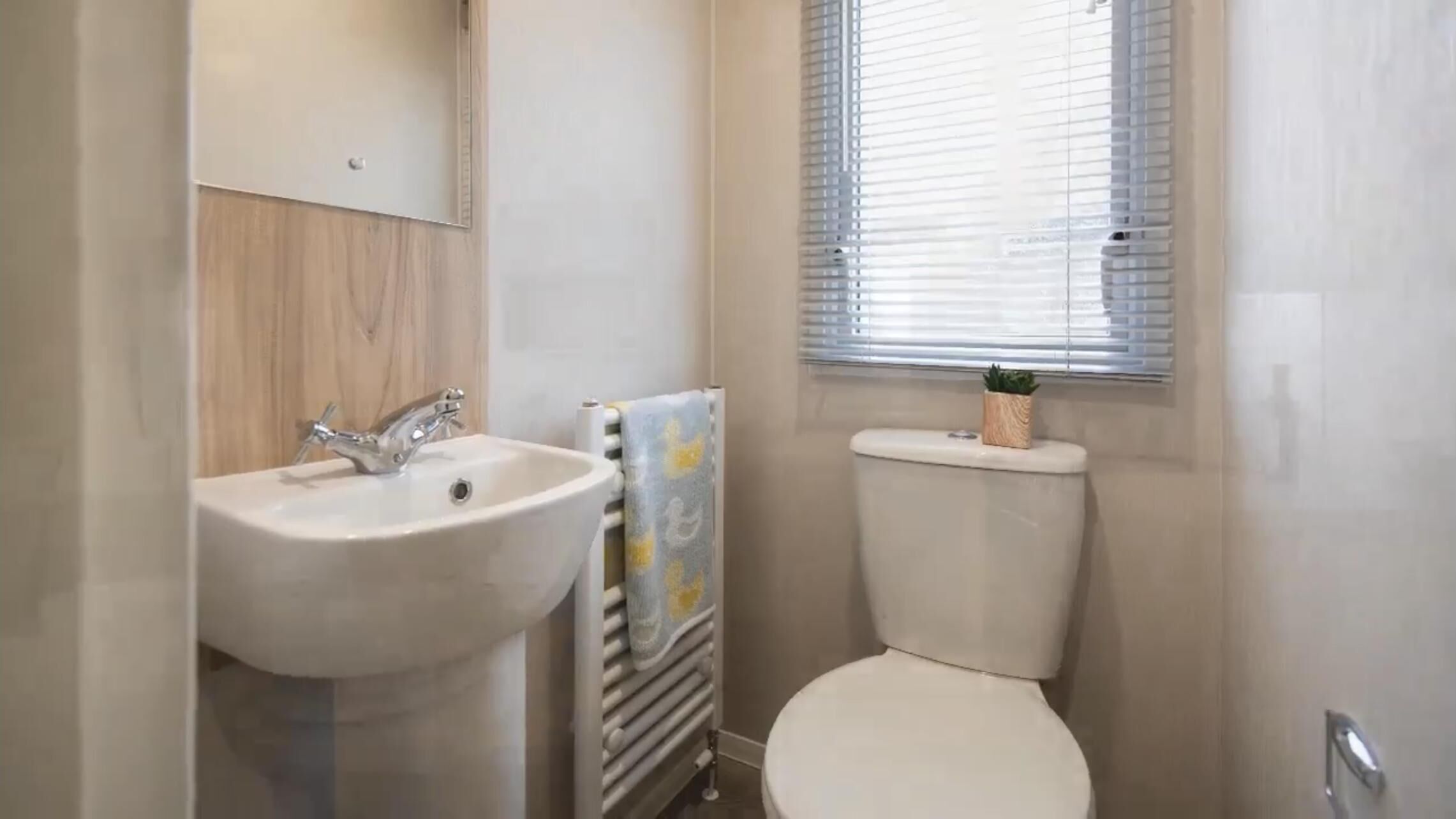 A bathroom with a sink, toilet, and window with blinds.