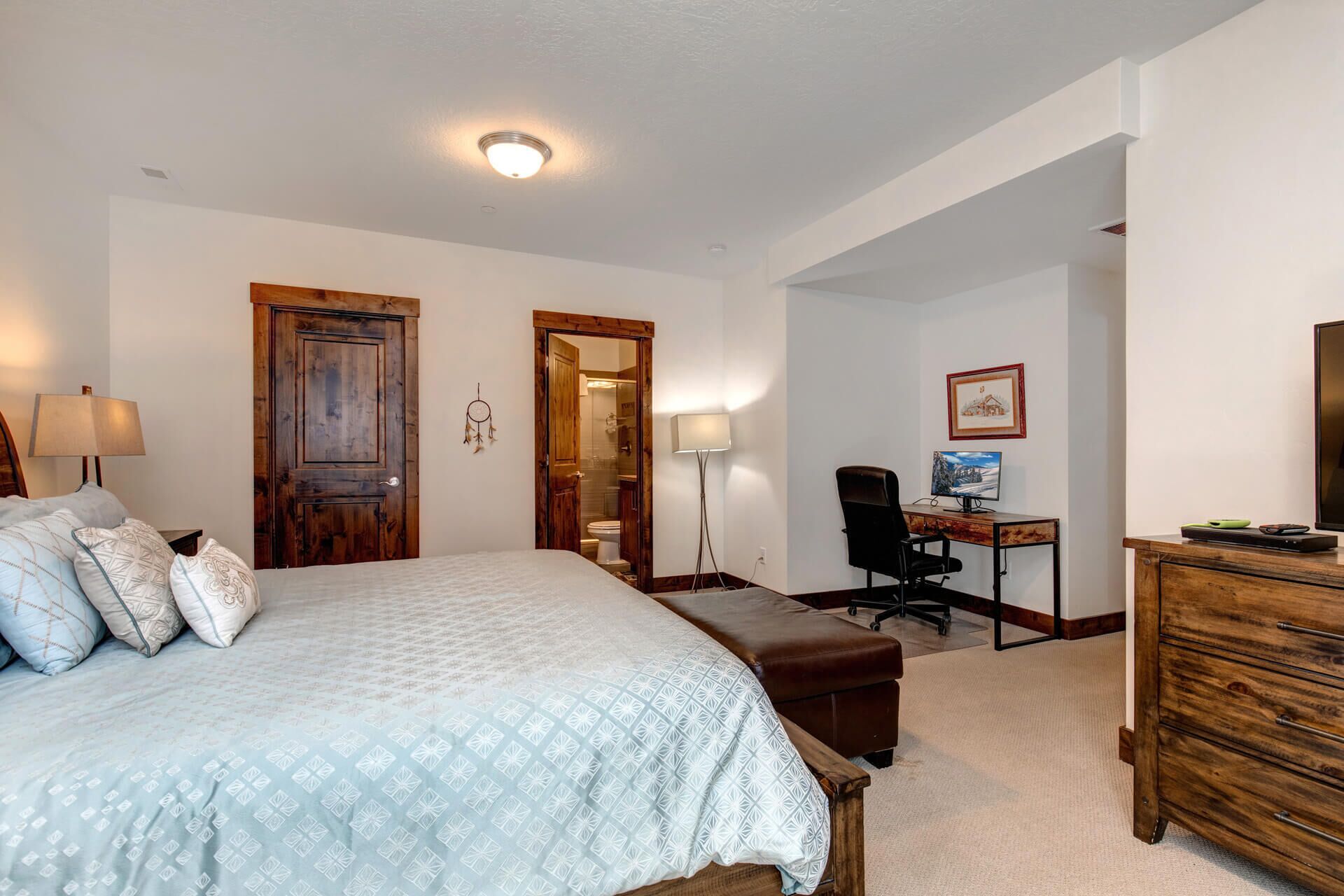 A bedroom with a bed, a desk, a chair, and a dresser.