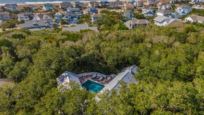 Un quartier résidentiel en bord de mer, avec des maisons, une piscine et une plage en arrière-plan.