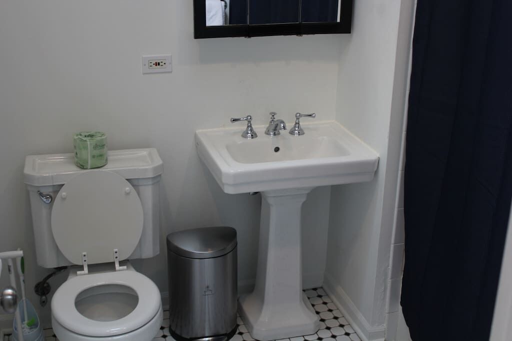 A bathroom with a toilet, sink, and trash can.