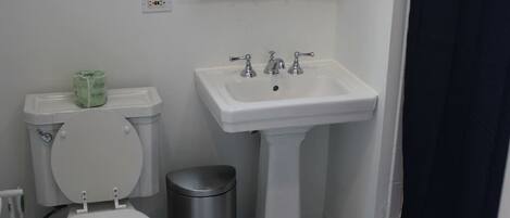 A bathroom with a toilet, sink, and trash can.