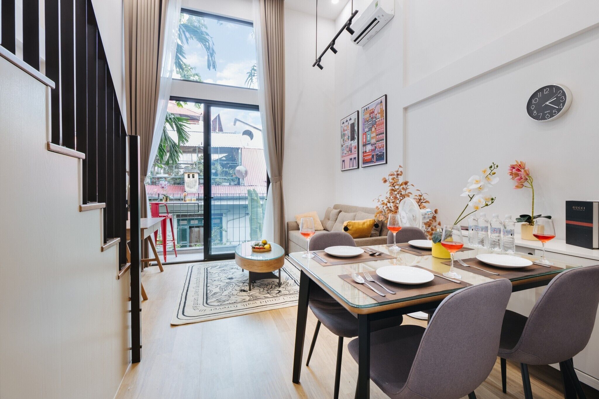 A modern dining area with a glass table, chairs, and a view of the outside.
