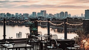 A restaurant with outdoor seating overlooking a city skyline and a body of water. - Margaery Boutique Apartment (Hanoi)