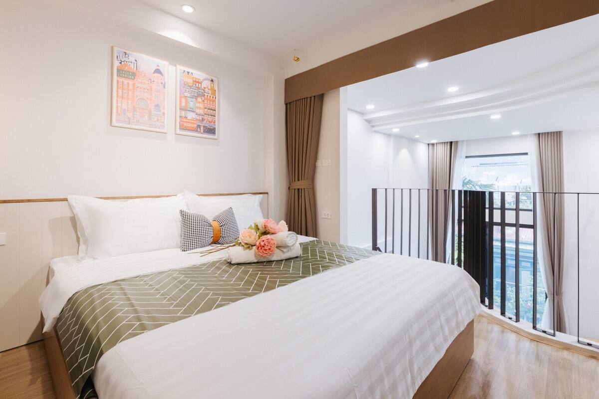 Een hotelkamer met een groot bed, uitzicht op de stad en een balkon met gordijnen.