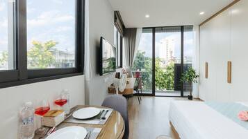 Une chambre d’hôtel moderne dotée d’un coin repas, d’un lit et d’un balcon offrant une vue sur la ville.