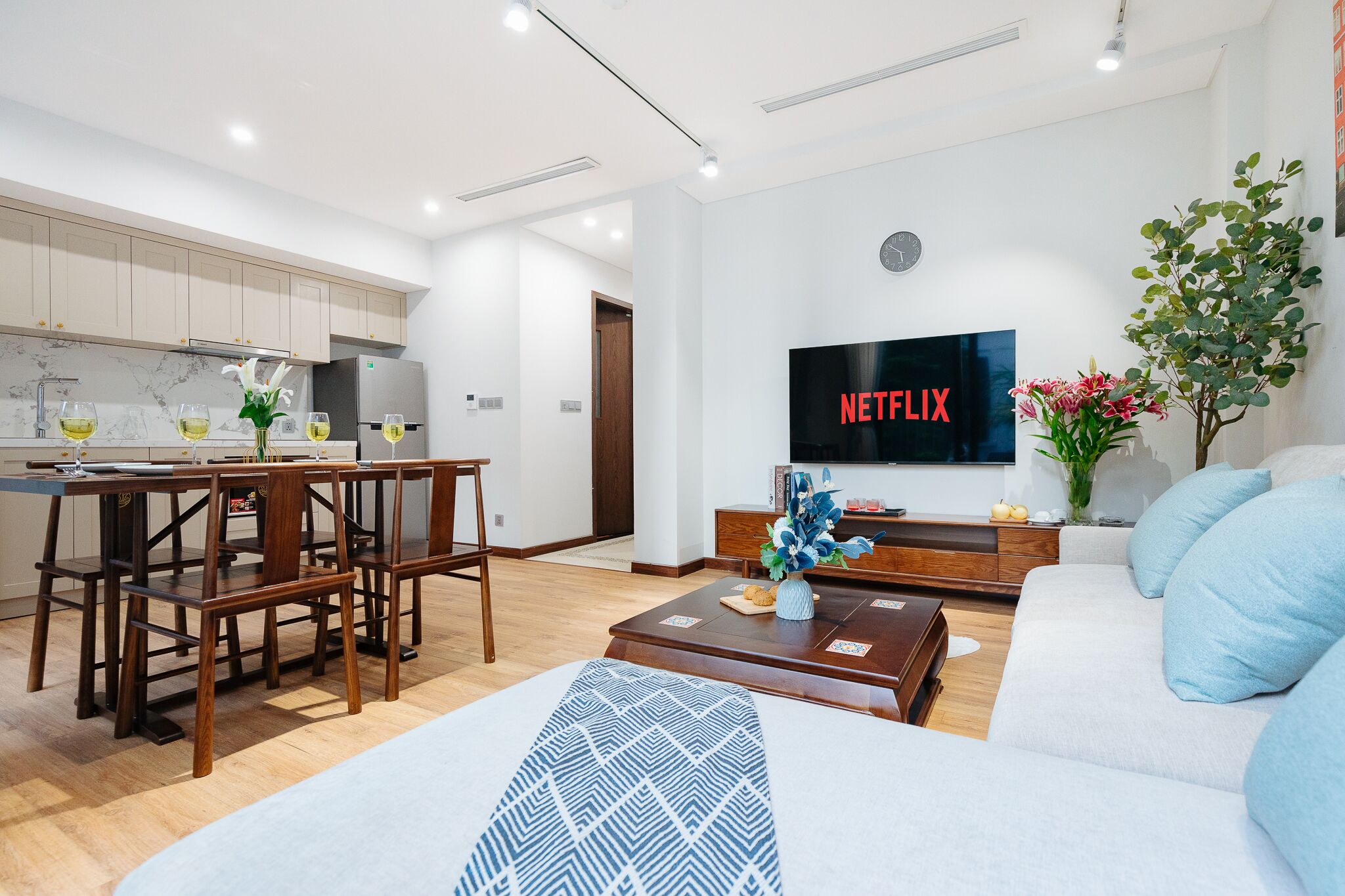 En moderne stue med sofa, sofabord og et fjernsyn, der viser 'NETFLIX'.