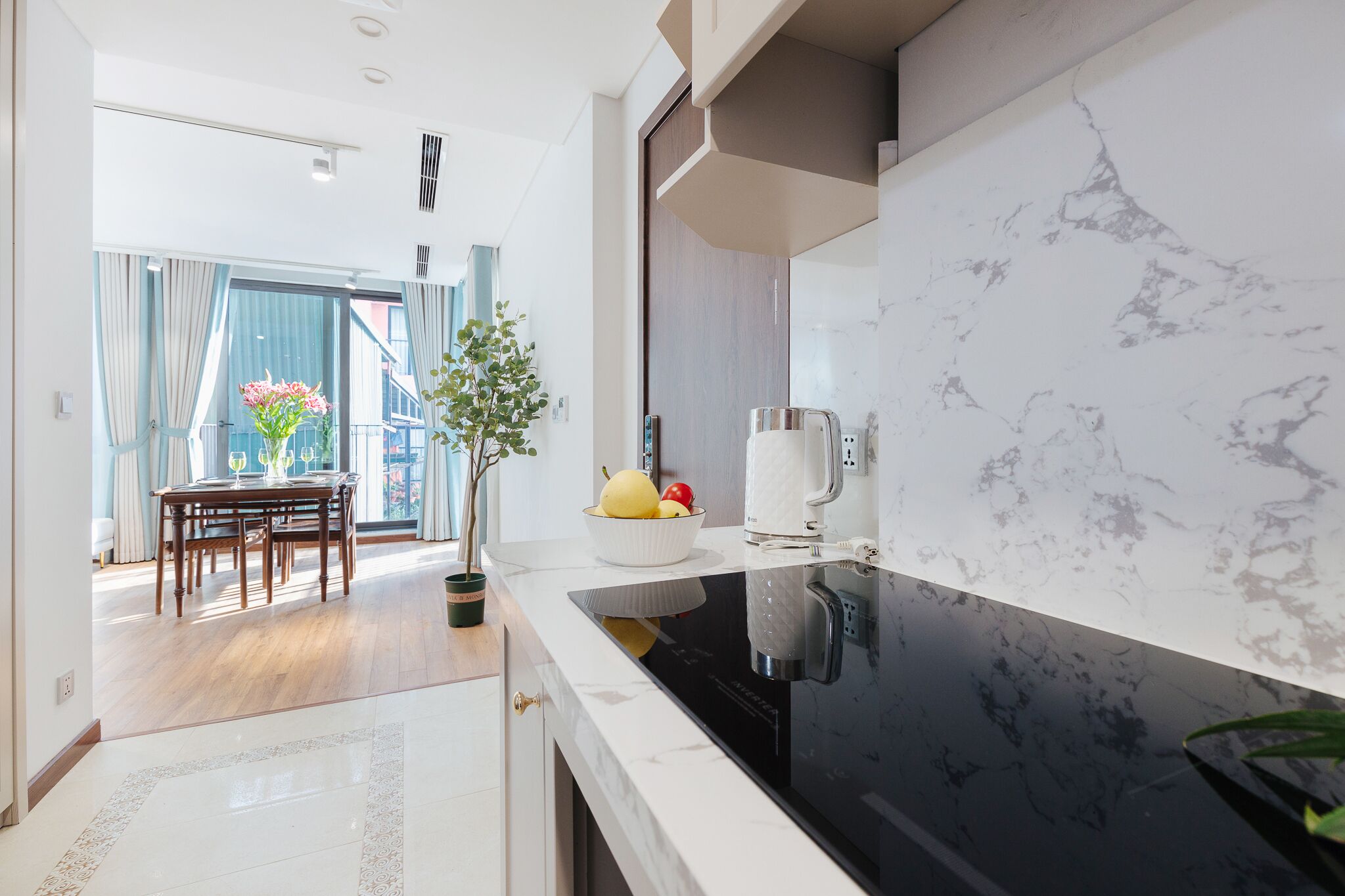 A modern kitchen with a black stove, white marble backsplash, and a dining area with a table and chairs.