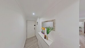 A hallway with a white door, a white console table with decorative items, and a mirror with a rustic frame. - PREMIUM HABITAT LA RIERA (Pineda de Mar)