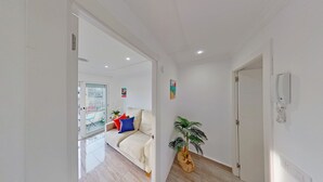 A modern living room with a sofa, a potted plant, and a door leading to another room. - PREMIUM HABITAT LA RIERA (Pineda de Mar)