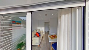 A modern interior with a sofa, a dining table with a pizza, and a view through a glass door. - PREMIUM HABITAT LA RIERA (Pineda de Mar)