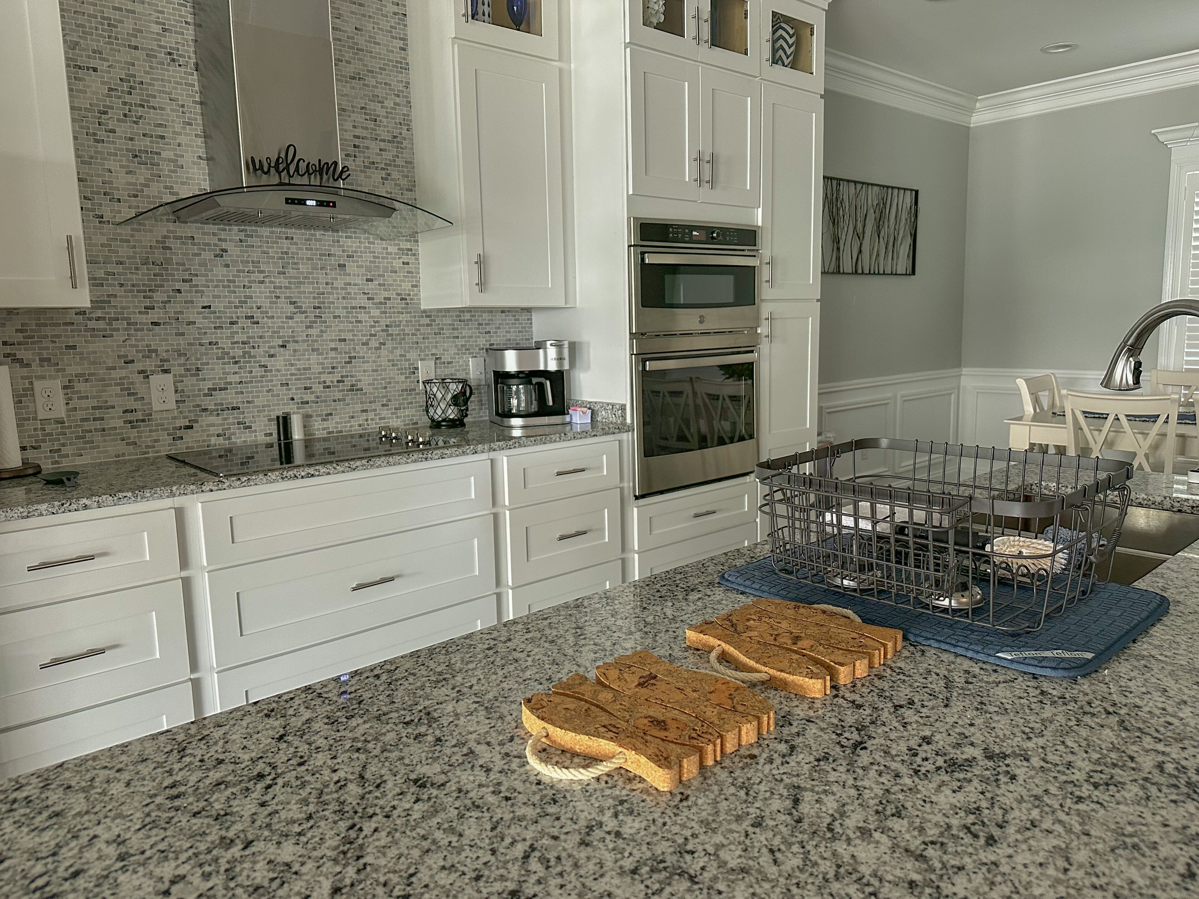 A kitchen with white cabinets, a brick backsplash, and a coffee maker.