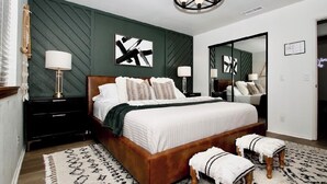 Ein Schlafzimmer mit Bett, Nachttischen, einem Spiegel und einer Chandelier.