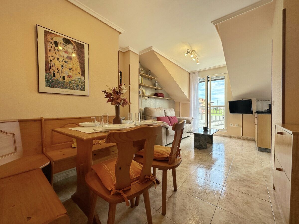 Un comedor con muebles de madera, un cuadro en la pared y una escalera que lleva a un balcón.