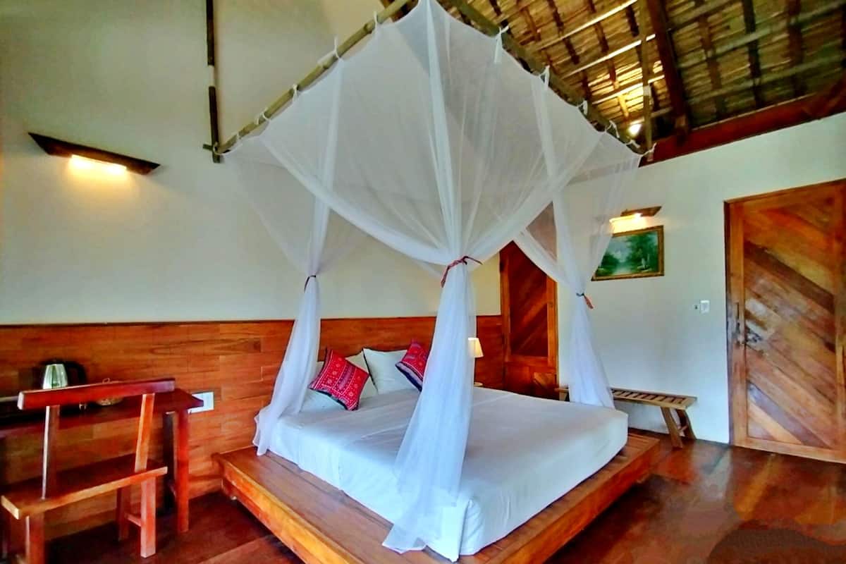 Una cama con dosel, muebles de madera y un cuadro en la pared.