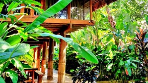 A wooden structure with a thatched roof surrounded by lush greenery. - Resort Pù luông Boutique Garden (Pu Luong)