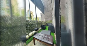 A patio area with outdoor furniture, a barbecue grill, and a green artificial turf.