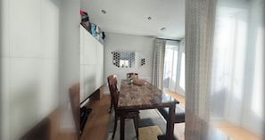 Un coin repas comprenant une table en bois, des chaises, un meuble blanc et un élément décoratif mural.