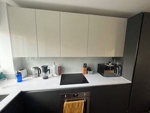 A modern kitchen with a black countertop, white cabinets, a built-in oven, and a coffee maker.
