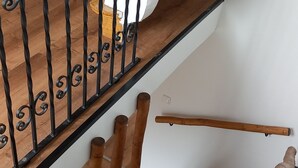 Un escalier en bois avec une rampe en métal noir et une main courante en bois.