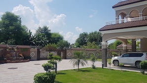 A gated residential area with a white SUV parked in front of a house with a tiled roof and a balcony. - Entire 6-bed Garden Villa (Chakswari)