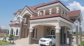 A modern two-story house with a white and brown color scheme, featuring a covered front porch and a white SUV parked in front.