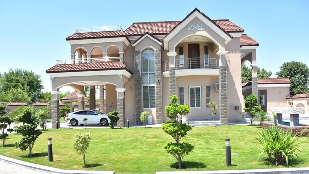 A large, two-story house with a covered driveway, a car parked in front, and a well-maintained lawn with small trees. - Entire 6-bed Garden Villa (Chakswari)