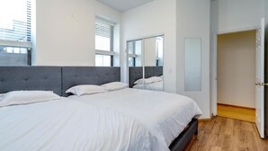 A bedroom with a large bed, a mirror, and a door leading to another room.
