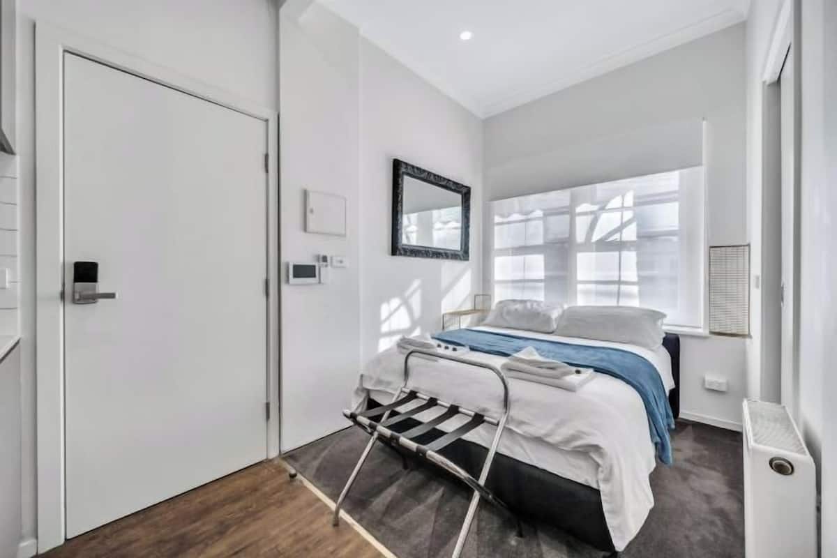 Quarto com cama, janela, radiador e porta.