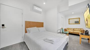 A hotel room with a large bed, a sofa, a coffee table, and a TV.