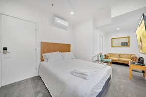 A hotel room with a large bed, a sofa, a coffee table, and a TV.