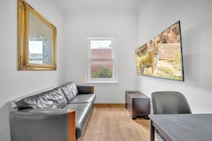 Ein modernes Wohnzimmer mit einer Ledersofa, einem Holztisch, einem Fernseher und einem großen gerahmten Bild eines Tigers.