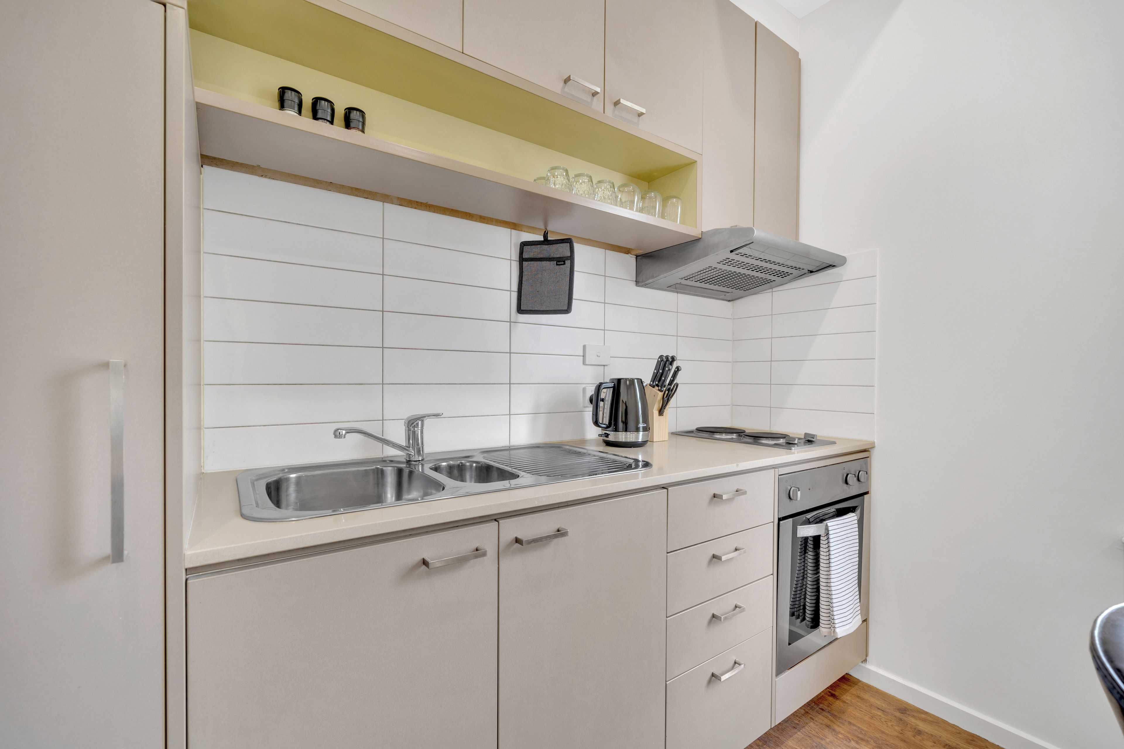 A modern kitchen with a double sink, stainless steel appliances, and a built-in oven.