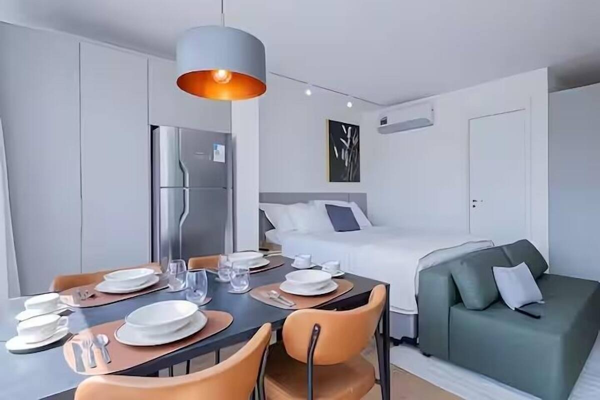 Moderni hotellihuone, jossa on ruokailutila, sänky ja vihreä sohva.