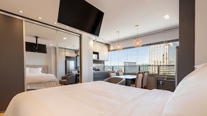 Une chambre d’hôtel moderne dotée d’un grand lit, d’un coin repas et offrant une vue sur la ville.