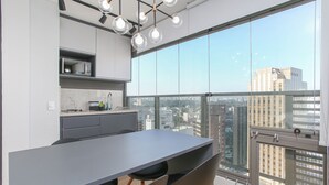 Une cuisine moderne dotée d’un grand îlot central, d’un four à micro-ondes et offrant une vue sur la ville grâce à de grandes fenêtres.
